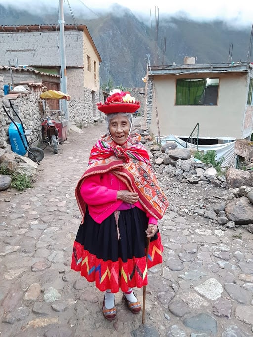 Cute short Andean woman in bright Pink traditional dress in Ollantaytambo 