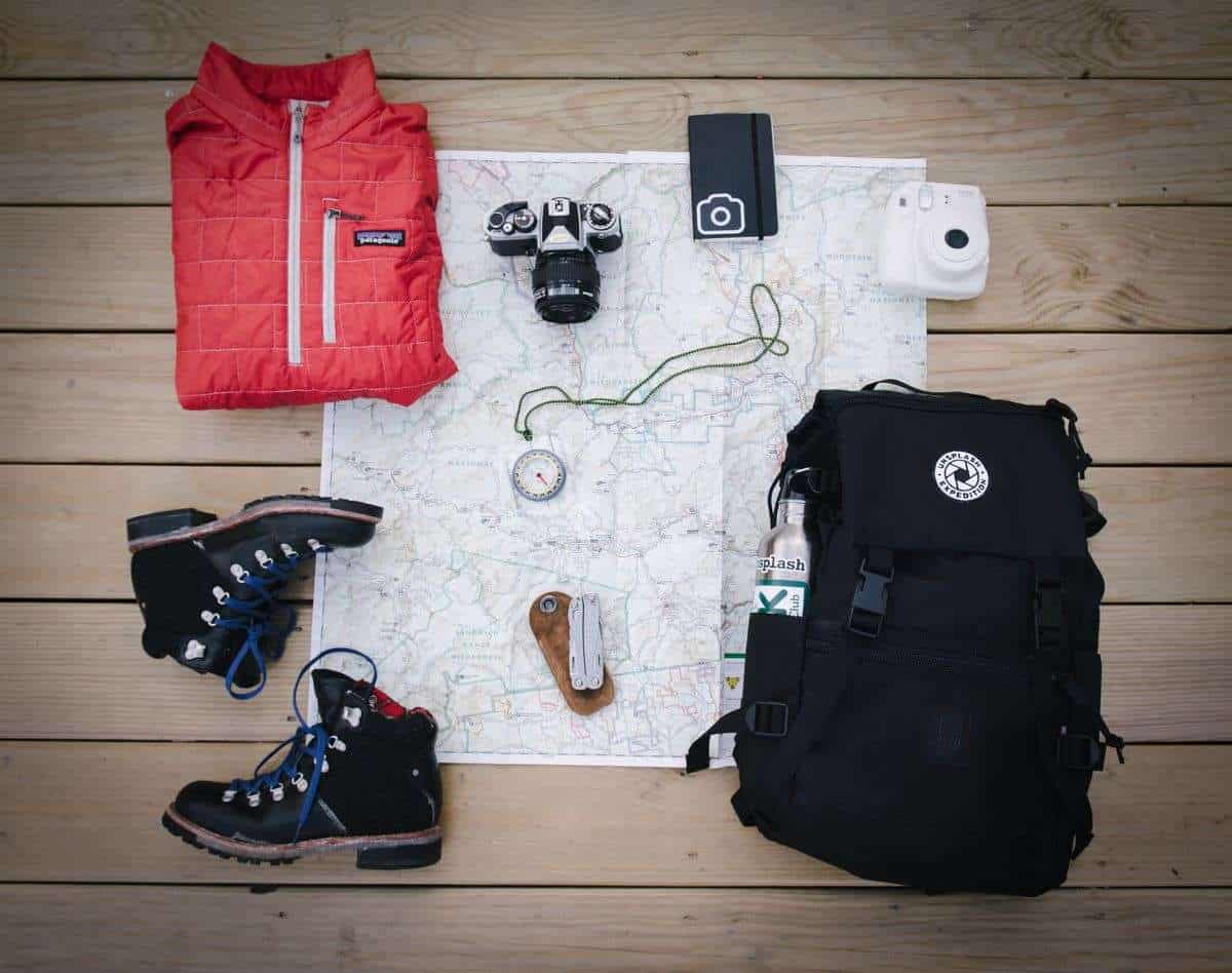 Map, Camera, travel boots, day-backpack and a compass lying on the floor, ready for packing #TravelGiftsandtravelMusthaves