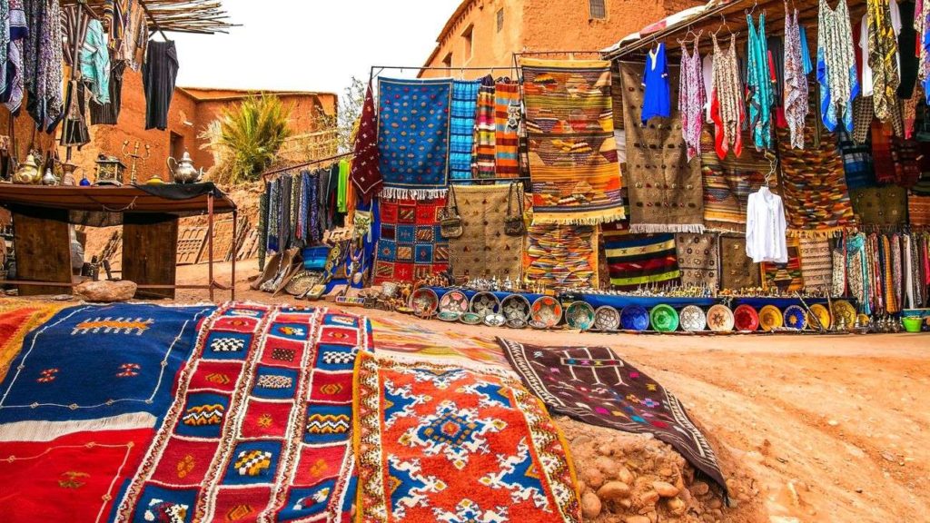 Street market in Morocco filled with colourful carpets and clothing 