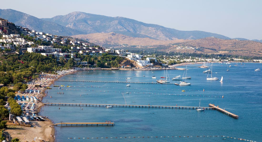 Yahsi Beach Bodrum, With a Tranquil scene of Yahsi Bay with umbrellas and sunbeds on the beach.