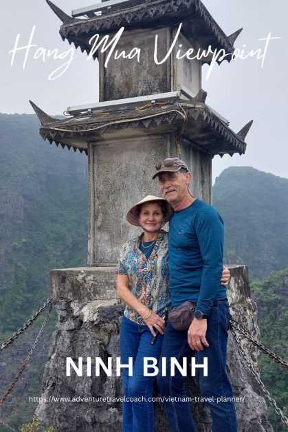 Couple standing on top of Hang Mua Viewpoint Vietnam overlooking the landscape in Vietnam after climbing 500 steps to get there.