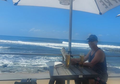 Man at Shelly Beach ski boat club having an ice cold beer overlooking the ocean.
