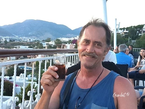 man enjoying a drink at an all-Inclusive hotel overlooking the mediteranean ocean in Gumbet Fethiye Turkey